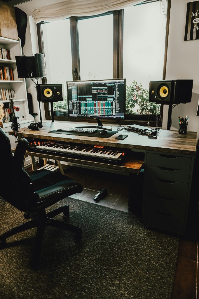 Home studio desk with a session on screen, nearfield monitors, and a keyboard